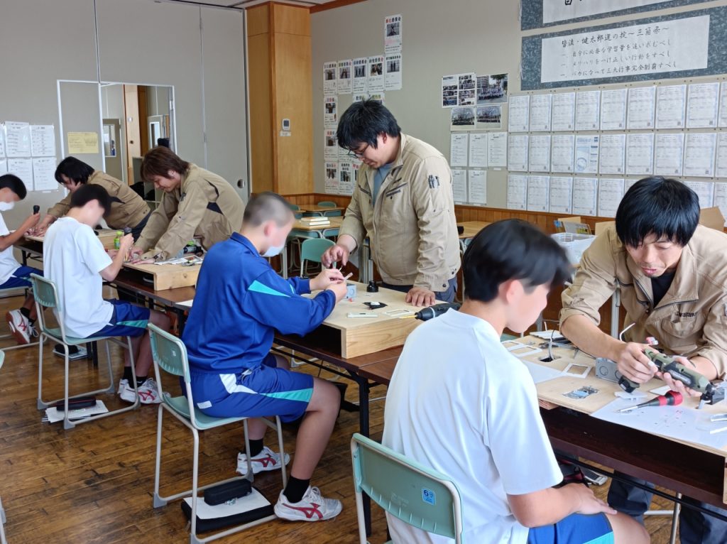 4人の社員と4人の生徒が1対1で配線工事体験を行っている。